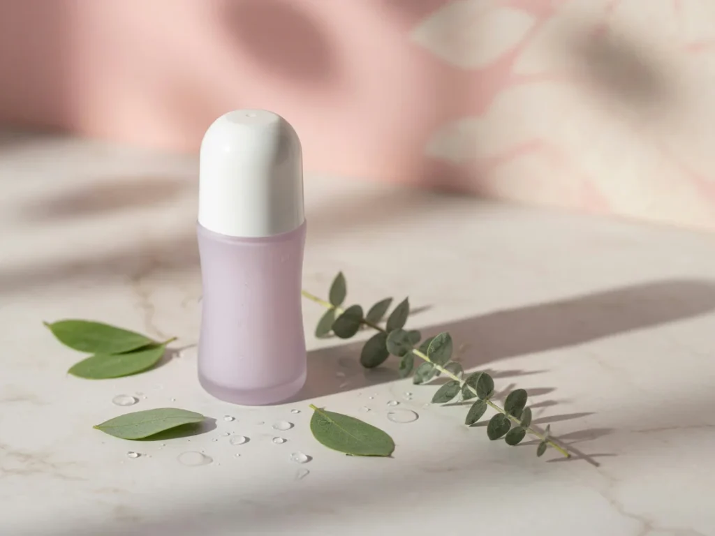 Elegant minimalist beauty photograph featuring a sleek roll-on antiperspirant bottle on a marble surface with soft pastel lig